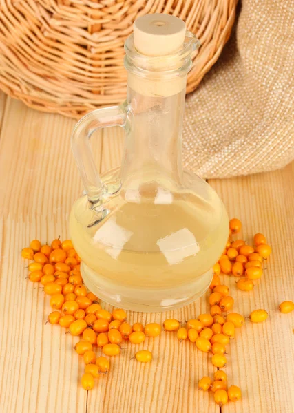 Decanter with sea buckthorn oil on wooden background close-up — Stock Photo, Image