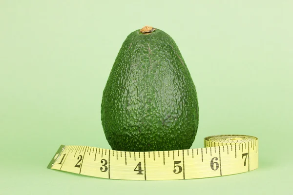 Avocado with measuring tape on green background — Stock Photo, Image