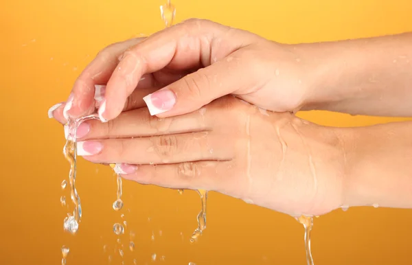 オレンジ色の背景のクローズ アップで女性の手を洗う — ストック写真