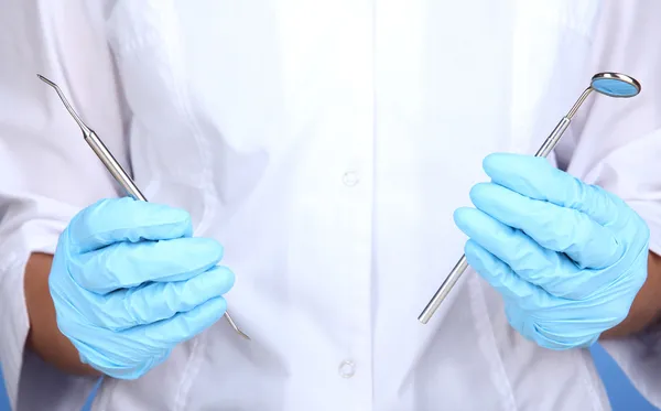 Les mains d'un dentiste en gants médicaux bleus avec des outils dentaires — Photo