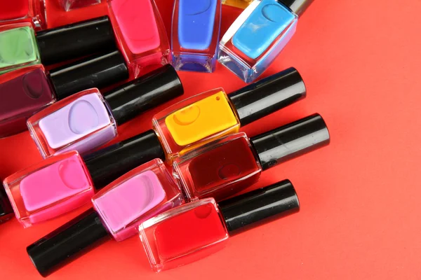 Group of bright nail polishes, on red background — Stock Photo, Image