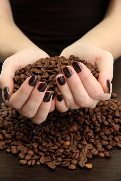 女的手与木制背景上的咖啡豆 — 图库照片