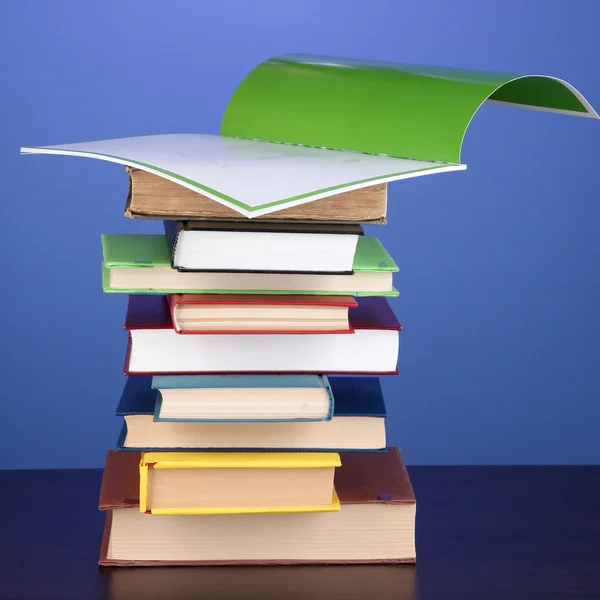 Montón de libros y revistas interesantes sobre mesa de madera sobre fondo azul —  Fotos de Stock