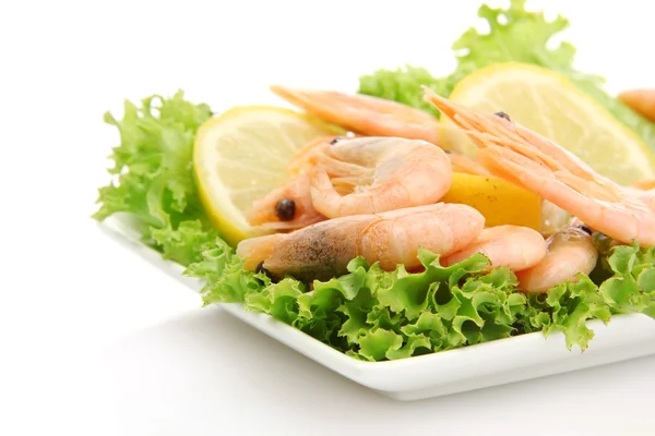 Camarones hervidos con hojas de limón y lechuga en plato, aislados en blanco —  Fotos de Stock