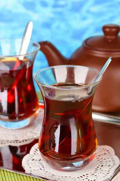 Glass of Turkish tea and kettle on color background — Stock Photo, Image