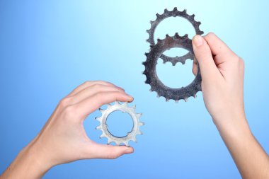 Metalik cogwheels mavi zemin üzerine onun elinde tutan adam