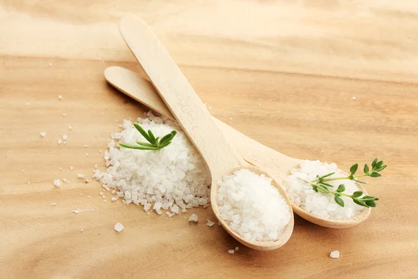 Salt in spoons with fresh rosemary and thyme on wooden background — Stock Photo, Image