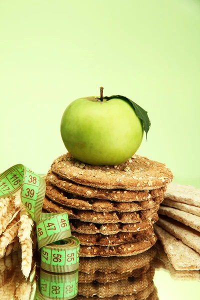 Leckeres Knäckebrot, Apfel, Maßband und Ohren, auf grünem Hintergrund — Stockfoto