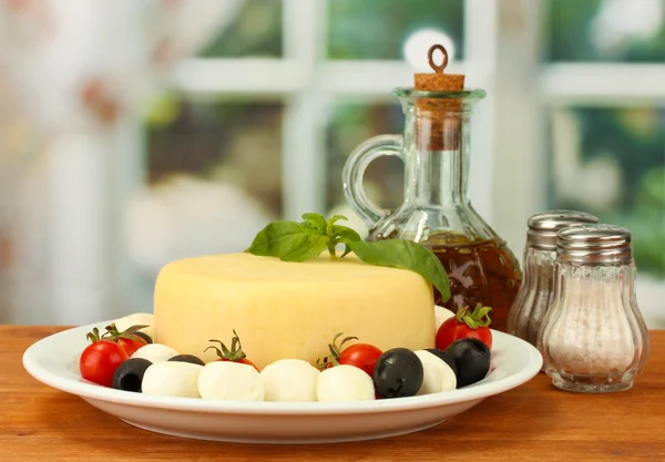 Kaas mozzarella met groenten in de plaat op houten tafel close-up — Stockfoto