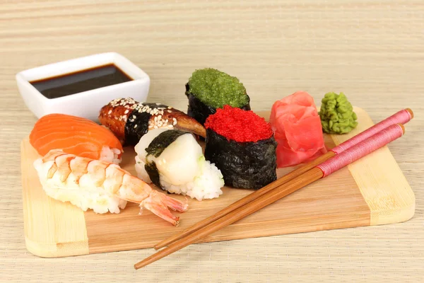Delizioso sushi servito su tavola di legno su tappetino di bambù — Foto Stock