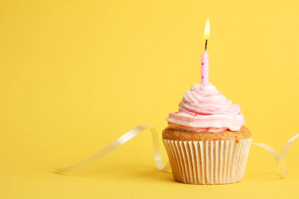 Вкусный день рождения кекс со свечой, на желтом фоне — стоковое фото