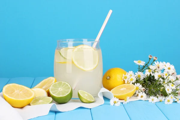 Limonada cítrica en banco de cristal de cítricos alrededor en la mesa de madera en la parte posterior azul —  Fotos de Stock