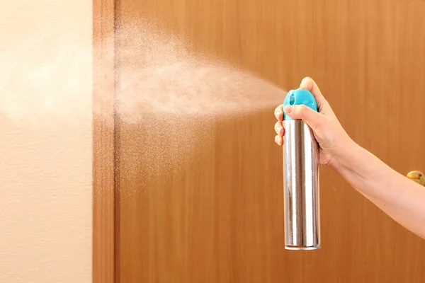 Sprayed air freshener in hand on room background — Stock Photo, Image