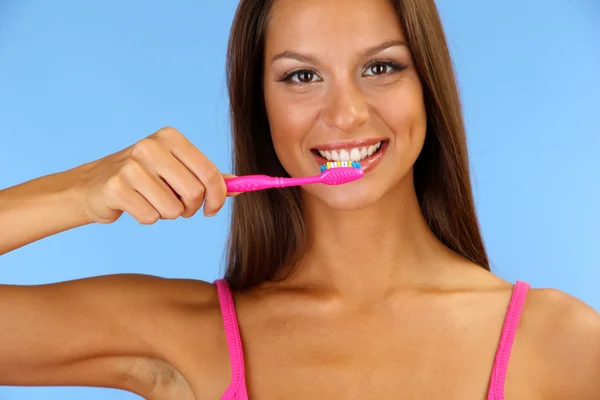 Hermosa joven con cepillo de dientes sobre fondo azul — Foto de Stock
