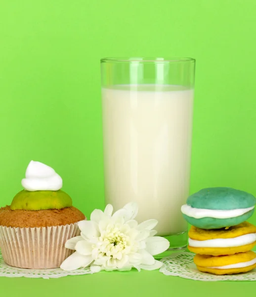 Glass of fresh new milk with cakes on green background — Stock Photo, Image