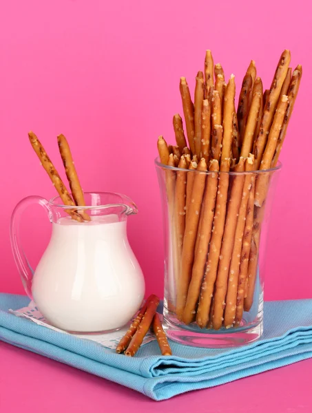 Palitos crocantes saborosos em copo de vidro no fundo rosa — Fotografia de Stock