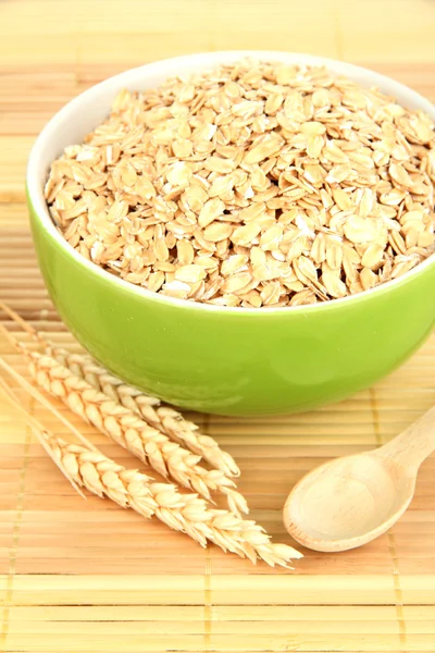 Cuenco verde lleno de copos de avena con cuchara de madera —  Fotos de Stock