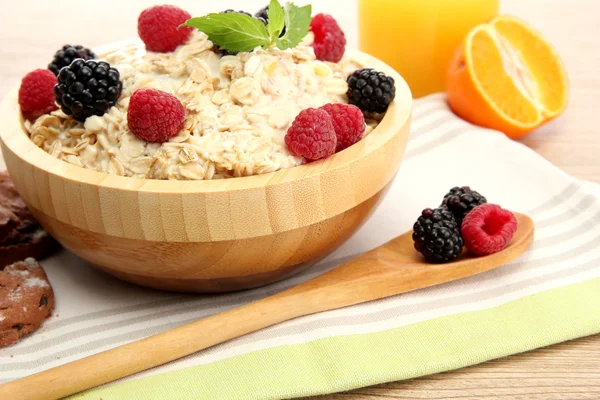 Leckeres Haferbrei mit Beeren und einem Glas Saft, auf einem Holztisch — Stockfoto