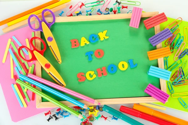 Pequeña pizarra con útiles escolares sobre fondo blanco. Volver a la escuela —  Fotos de Stock