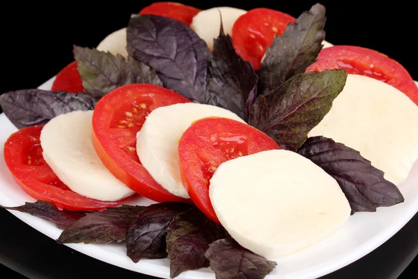 Вкусная моцарелла с помидорами на тарелке изолированы на черном — стоковое фото