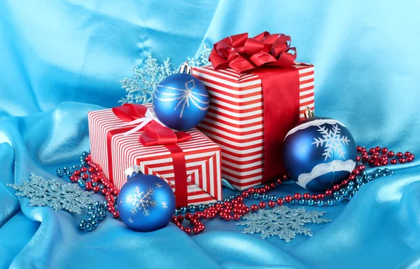 Regali rossi colorati con palline di Natale blu, fiocchi di neve e perline su blu — Foto Stock