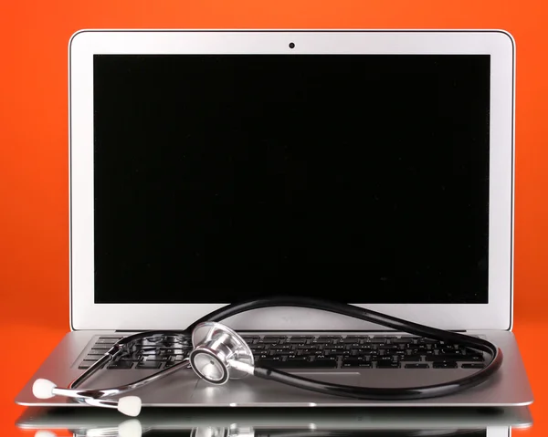 Silver notebook with a stethoscope on red background with reflection — Stock Photo, Image