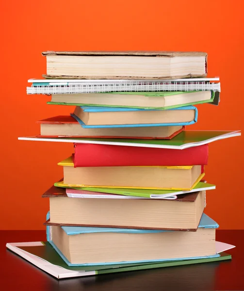 Stapel interessante boeken en de tijdschriften op houten tafel op rode achtergrond — Stockfoto