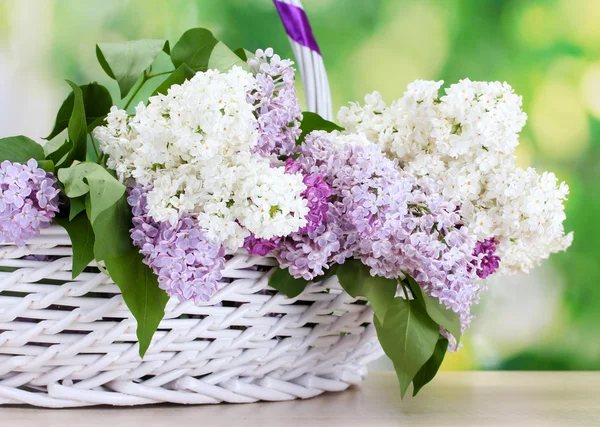 Hermosas flores lila en cesta sobre mesa de madera sobre fondo verde —  Fotos de Stock