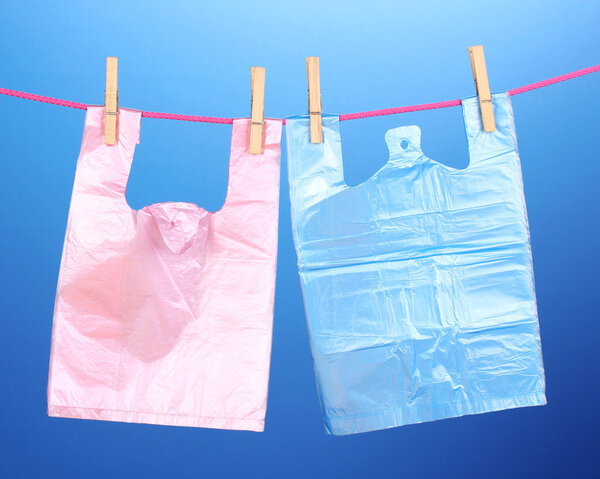 Целофановые мешки висят на веревке на синем фоне
