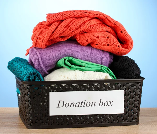 Donatie box met kleding op blauwe achtergrond close-up — Stockfoto