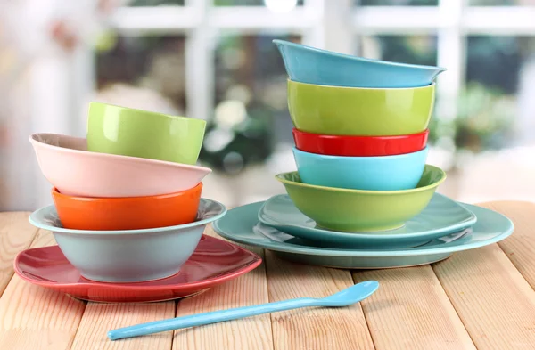 Colorful tableware on wooden table on window background — Stock Photo, Image