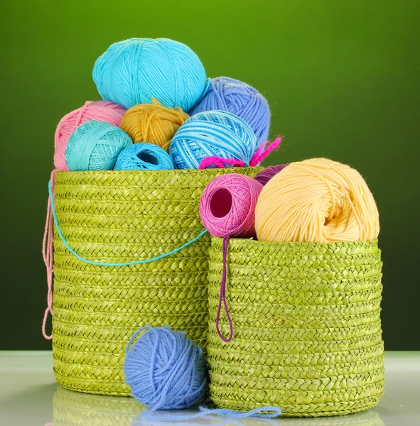 Fio colorido para tricô em cesta verde no fundo verde — Fotografia de Stock