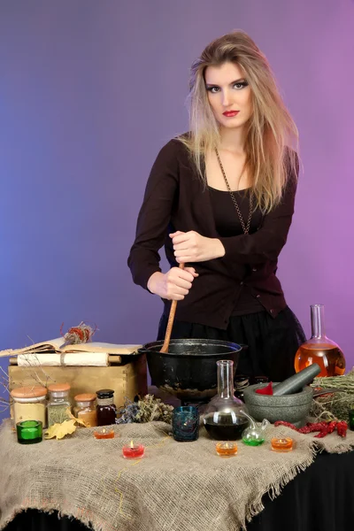 Halloween witch stirring in poison soup in her cauldron on color background — Stockfoto