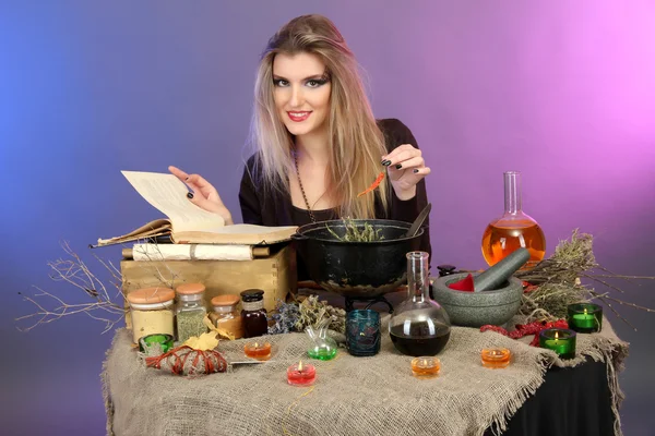 Halloween witch preparing poison soup in her cauldron on color background — Stok fotoğraf
