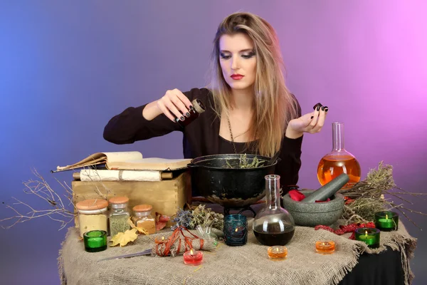 Halloween witch preparing poison soup in her cauldron on color background — Stockfoto