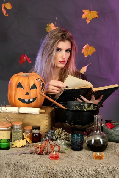 Halloween witch preparing poison soup in her cauldron on color background — Stok fotoğraf