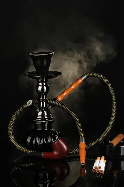 Herramientas para fumar - una cachimba, cigarro, cigarrillo y pipa sobre fondo negro — Foto de Stock