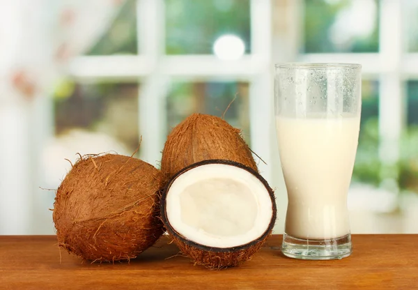 Vidro de leite de coco e cocos em mesa de madeira close-up — Fotografia de Stock