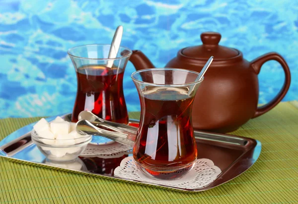 Glass of Turkish tea and kettle on color background — Stock Photo, Image