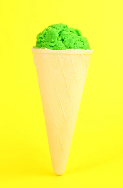 Cucharada del helado de kiwi en el cono de gofre sobre fondo amarillo — Foto de Stock