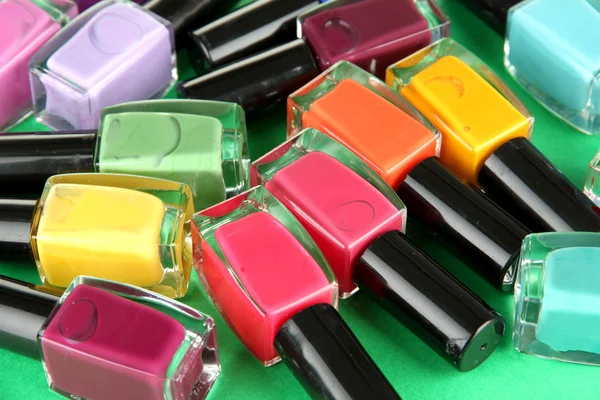 Group of bright nail polishes, on green background — Stock Photo, Image