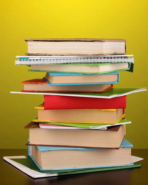 Stack of interesting books and magazines on wooden table on yellow backgrou — Stock Photo, Image