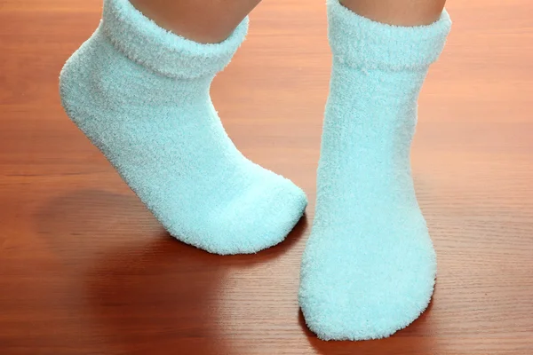 Πόδια θηλυκό σε μπλε κάλτσες στο φυλλόμορφο δάπεδο — Φωτογραφία Αρχείου
