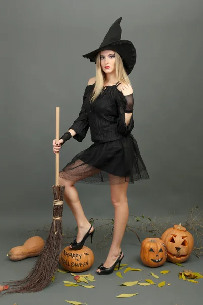 Halloween čarodějnice s koštětem na šedém pozadí — Stock fotografie