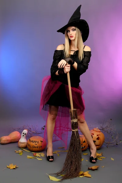 Хэллоуинская ведьма с метлой на цветном фоне — стоковое фото