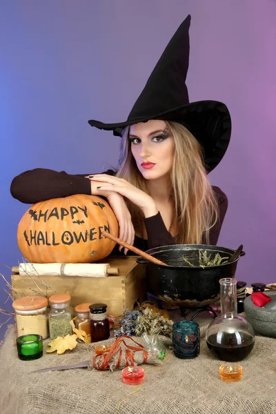 Хэллоуинская ведьма готовит ядовитый суп в котле на цветном фоне — стоковое фото