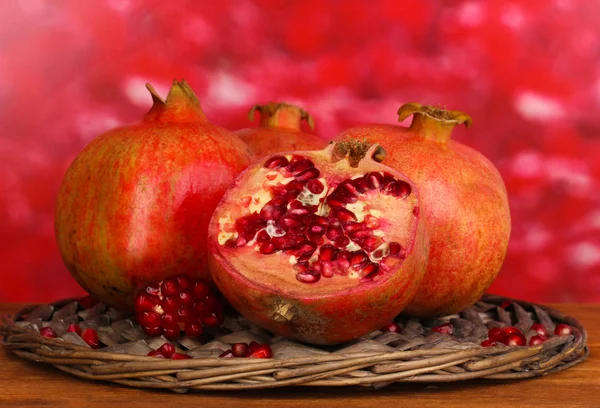 Zralé granátová jablka na proutěný stojan na dřevěný stůl na podzim pozadí — Stock fotografie