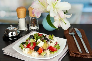 Restoran arka planında beyaz tabakta taze Yunan salatası.