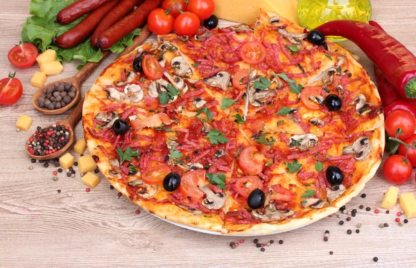 Läcker pizza, grönsaker och salami på träbord — Stockfoto