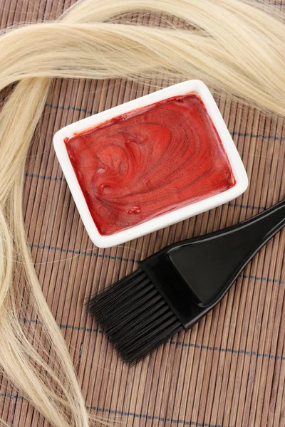 Tintura per capelli in ciotola e pennello per tintura su tappetino di bambù marrone, primo piano — Foto Stock